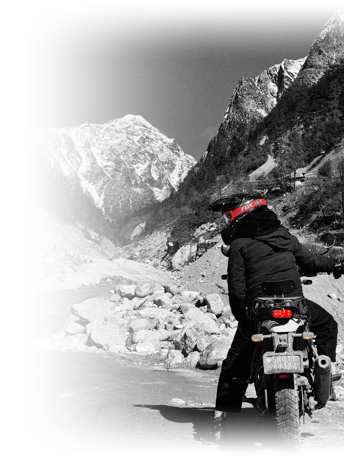 Rider on a motorbike facing snow-capped mountains